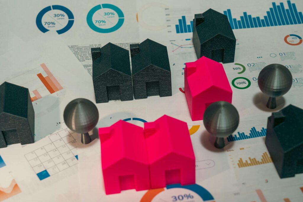 Colourful model houses on financial charts representing property investment and diversification © Pexels
