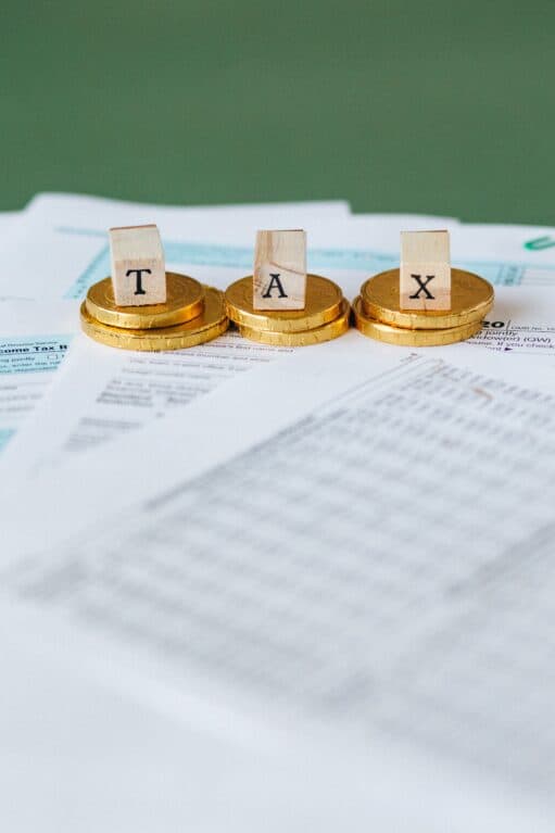Gold coins and tiles spelling TAX on financial documents.
